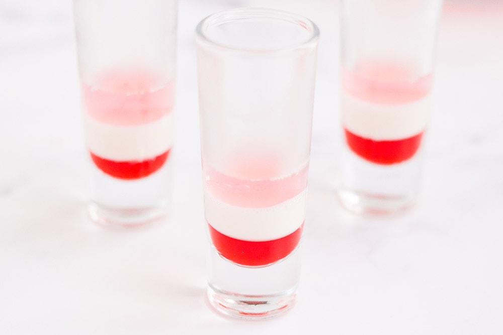 Three layers of jello in three dessert shooter glasses.