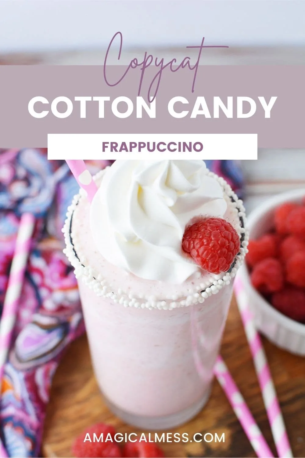 Cotton candy frapp with whipped cream and raspberries on a table.