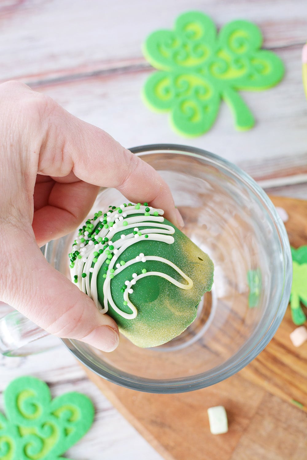 Dropping a leprechaun hot chocolate bomb into a glass.