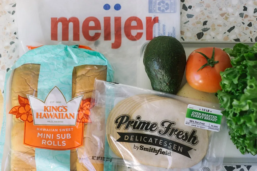 King's Hawaiian Mini Sub Rolls, a Meijer bag, Prime Fresh turkey, avocado, tomato and lettuce on a table. 