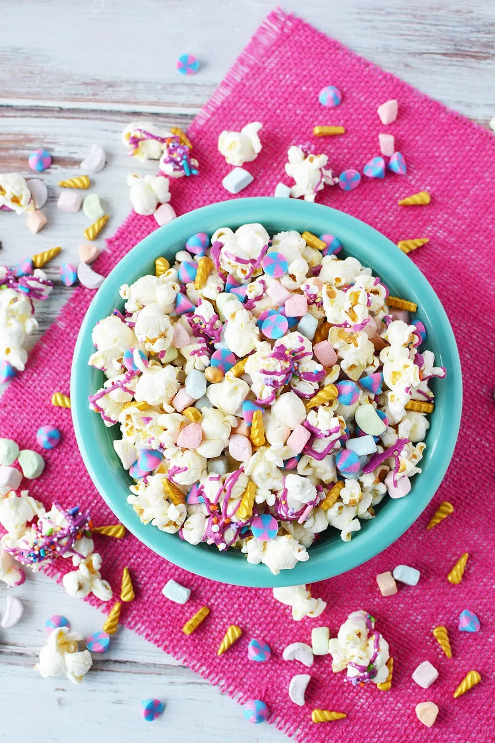 Overhead shot of unicorn popcorn in a blue bowl with a pink napkin.