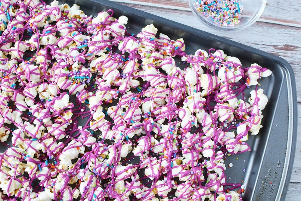 Pink candy melts drizzled over popcorn.