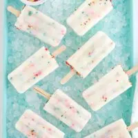 Several cake mix pops on a bed of ice in a blue tray.