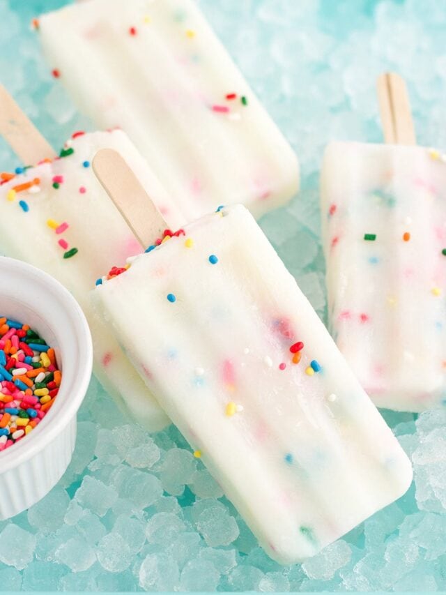 Cake popsicles laying on a bed of ice next to sprinkles.