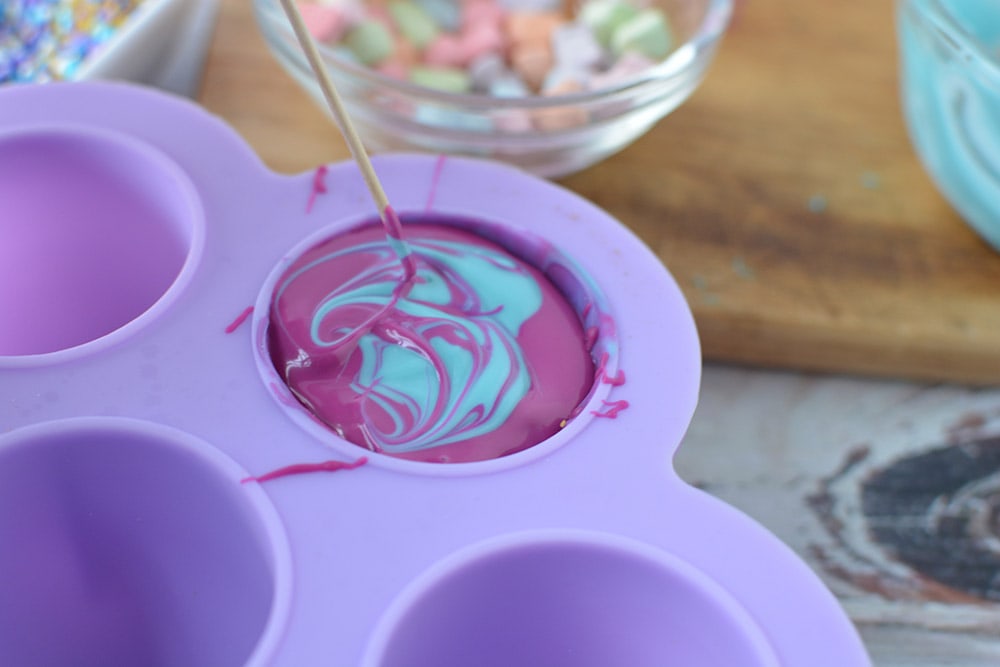 Purple and blue melted chocolate in a candy mold.