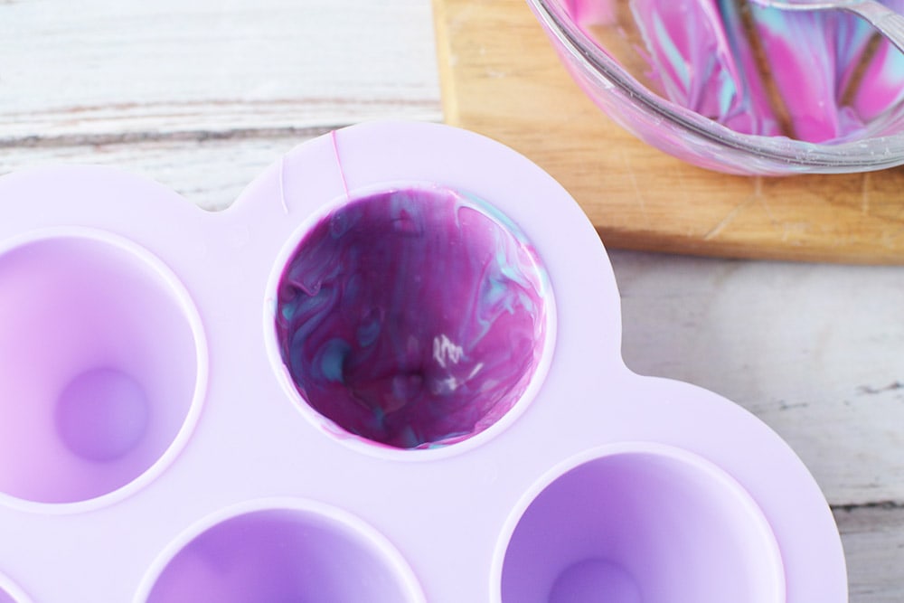 Candy mold lined with purple melted chocolate.