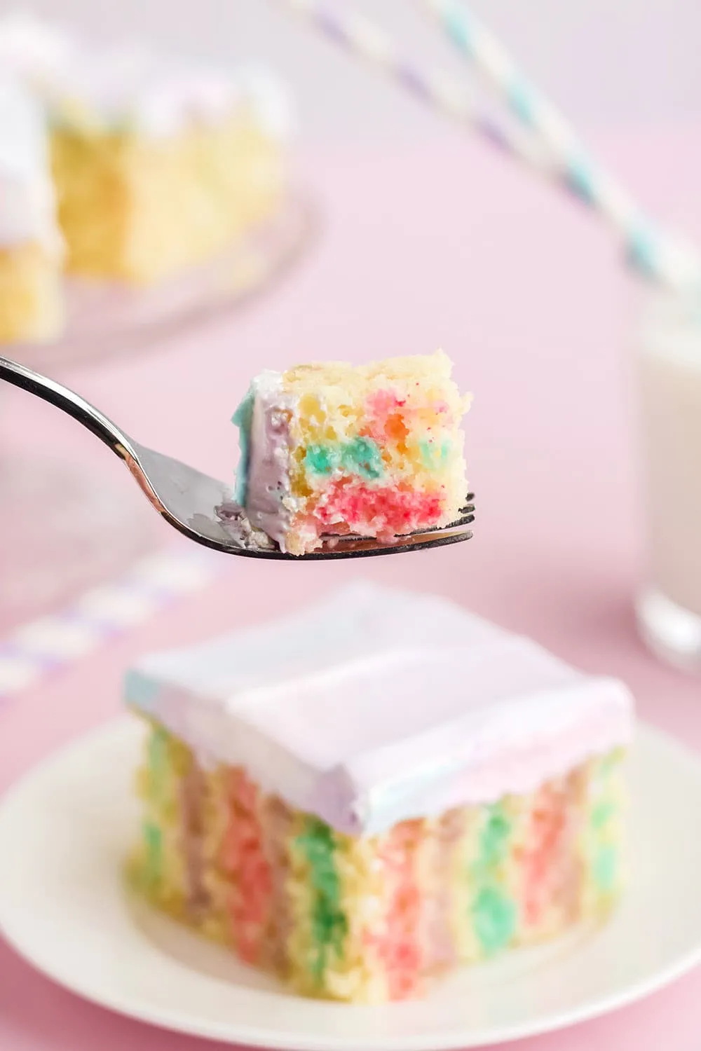 Fork with cake on it in front of a poke cake on a plate.