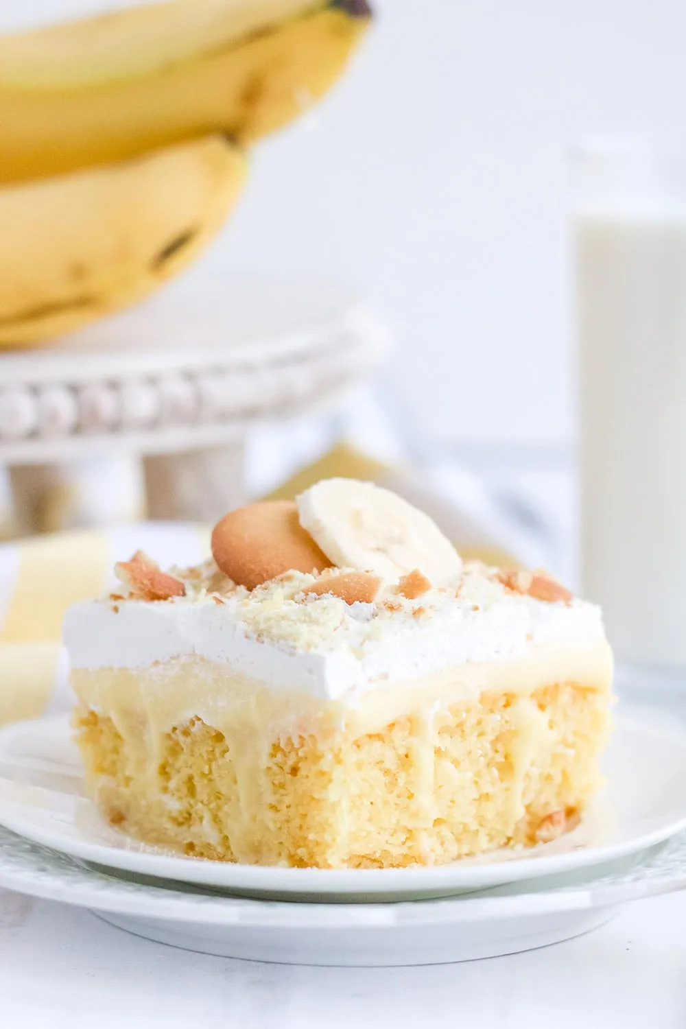 Yellow cake on a white plate with bananas and cookies.