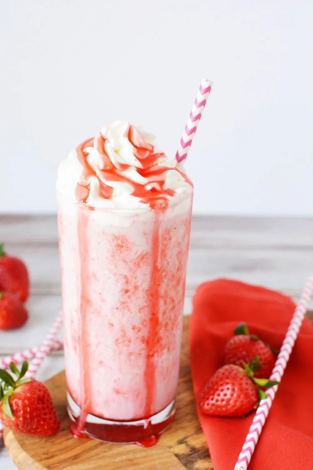 Glass of strawberry frappuccino next to strawberries.