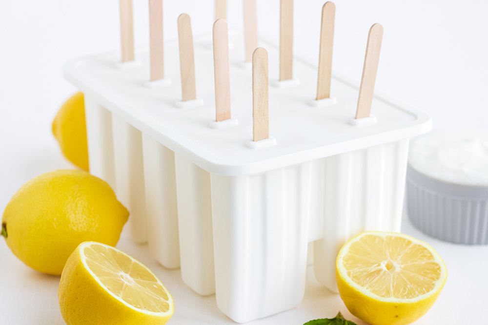 White silicone popsicle mold with lemons around it.