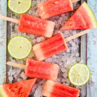 Watermelon popsicles on a tray with ice.