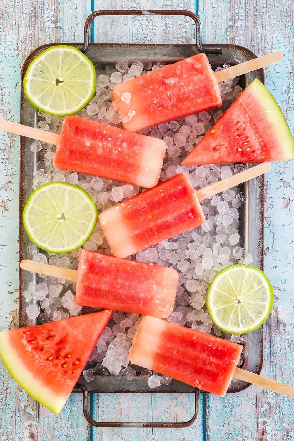 Watermelon popsicles on a tray with ice.