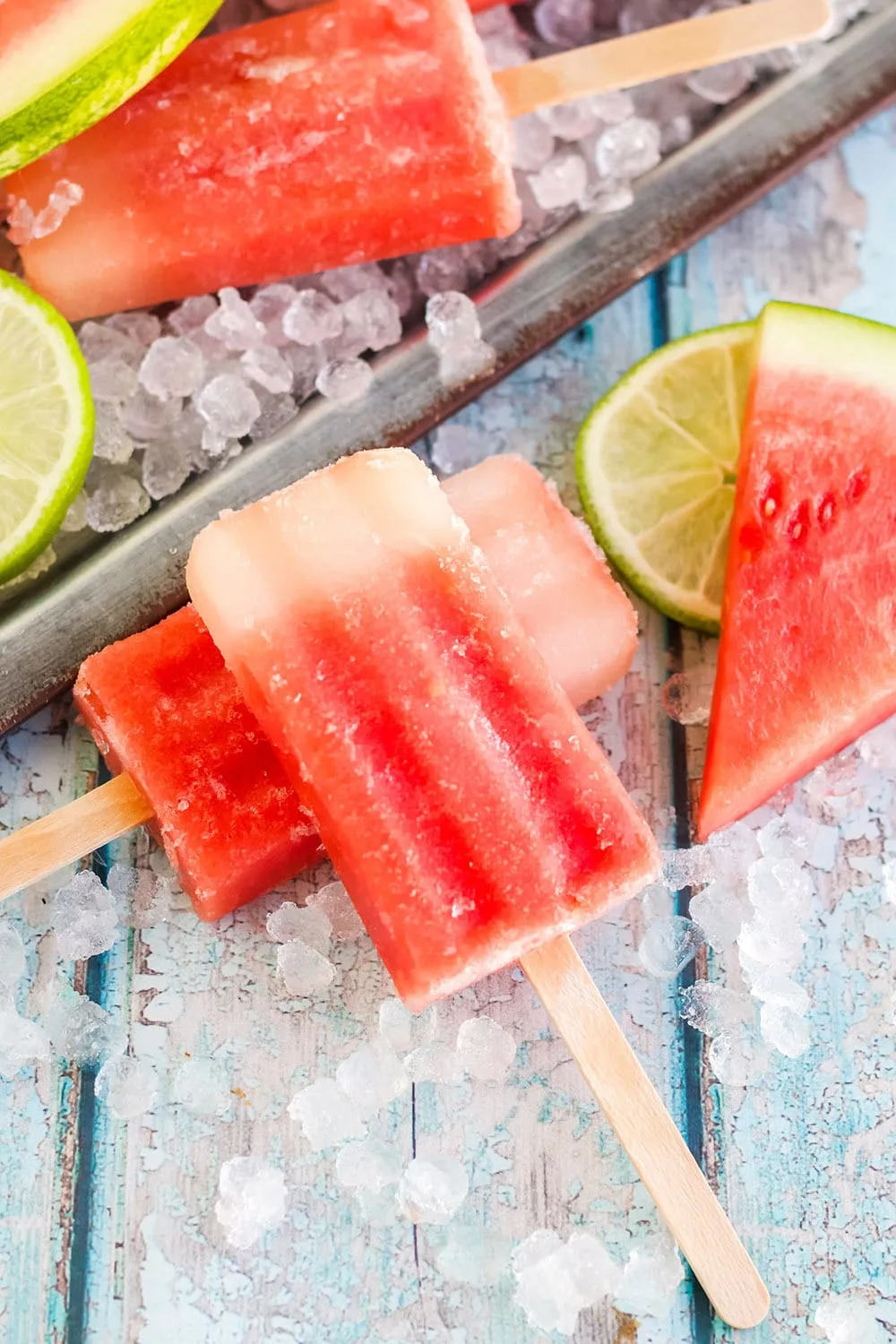 Popsicles on a table next to watermelon.