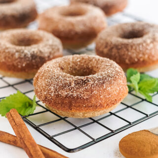 Apple cider donuts with cinnamon on a rack.