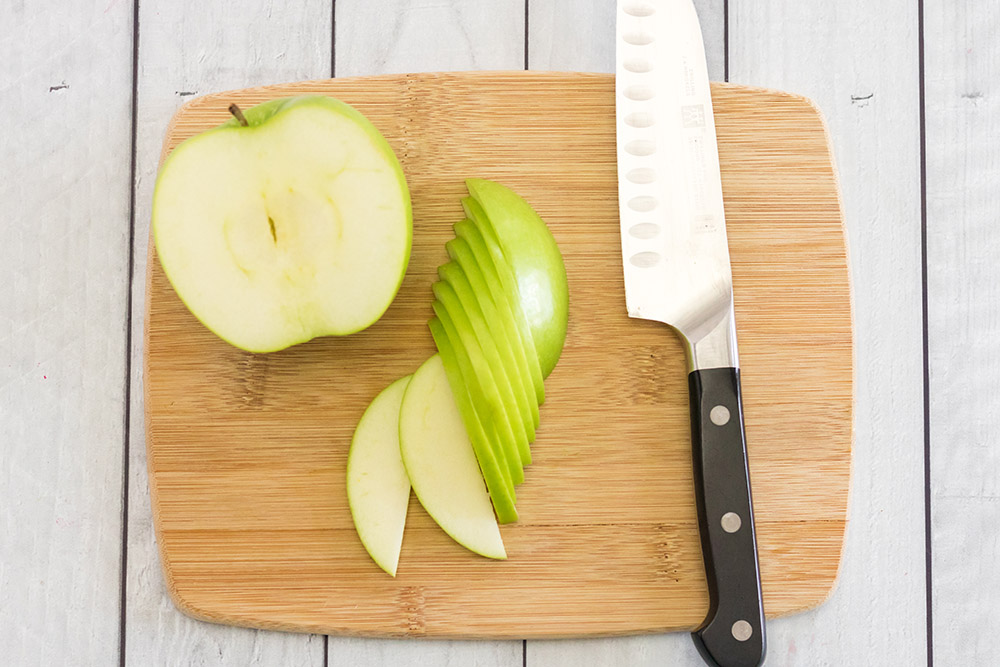 Slicing green apples on a cutting board.
