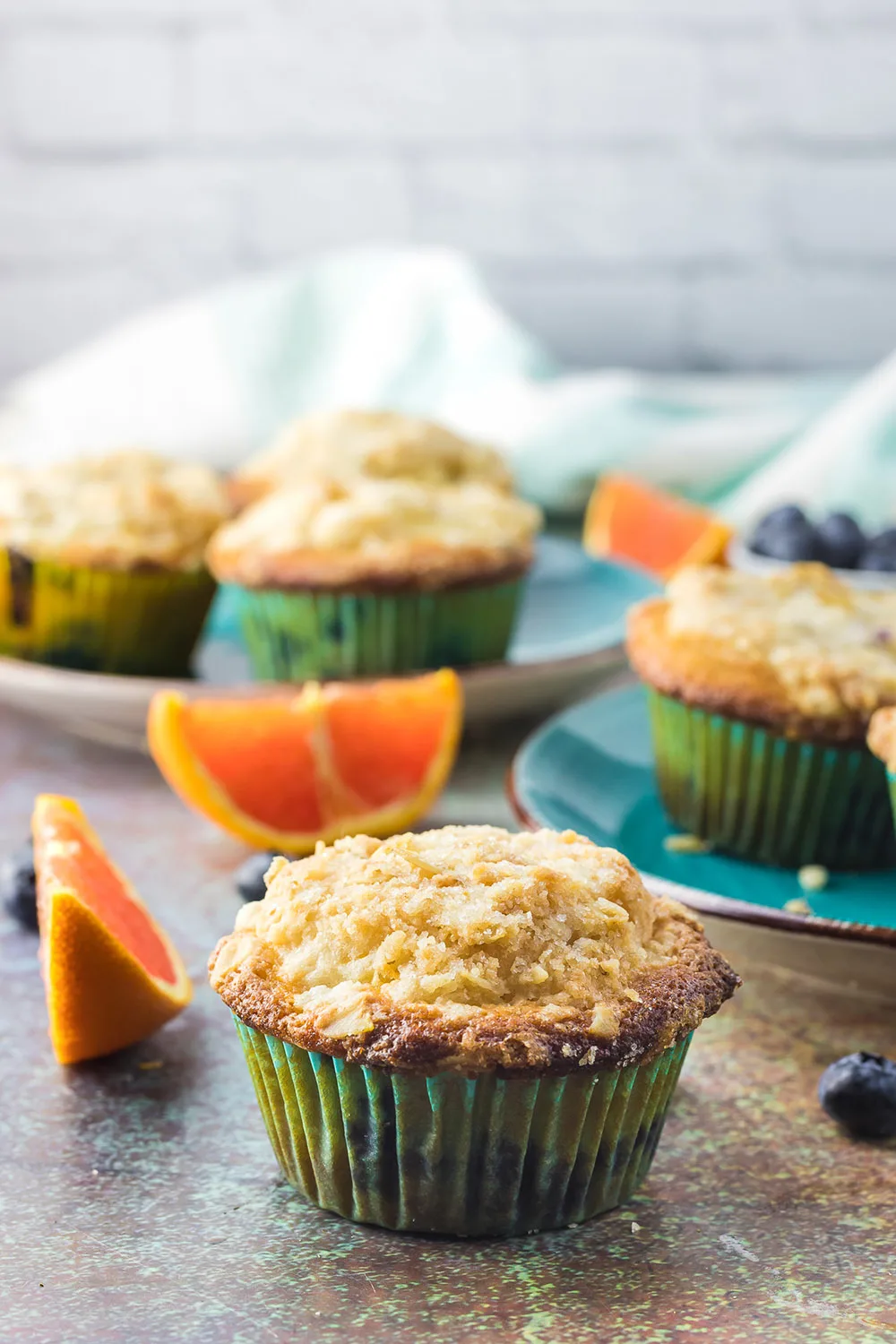 Blueberry muffins on a table with orange slices.