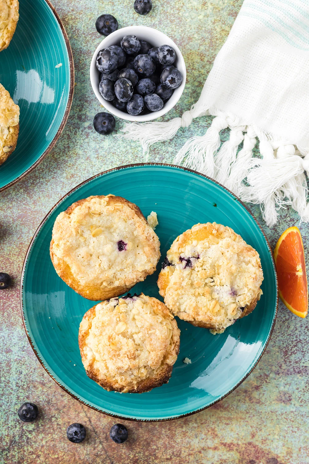 Overhead image of three blueberry muffins on a blue plate.