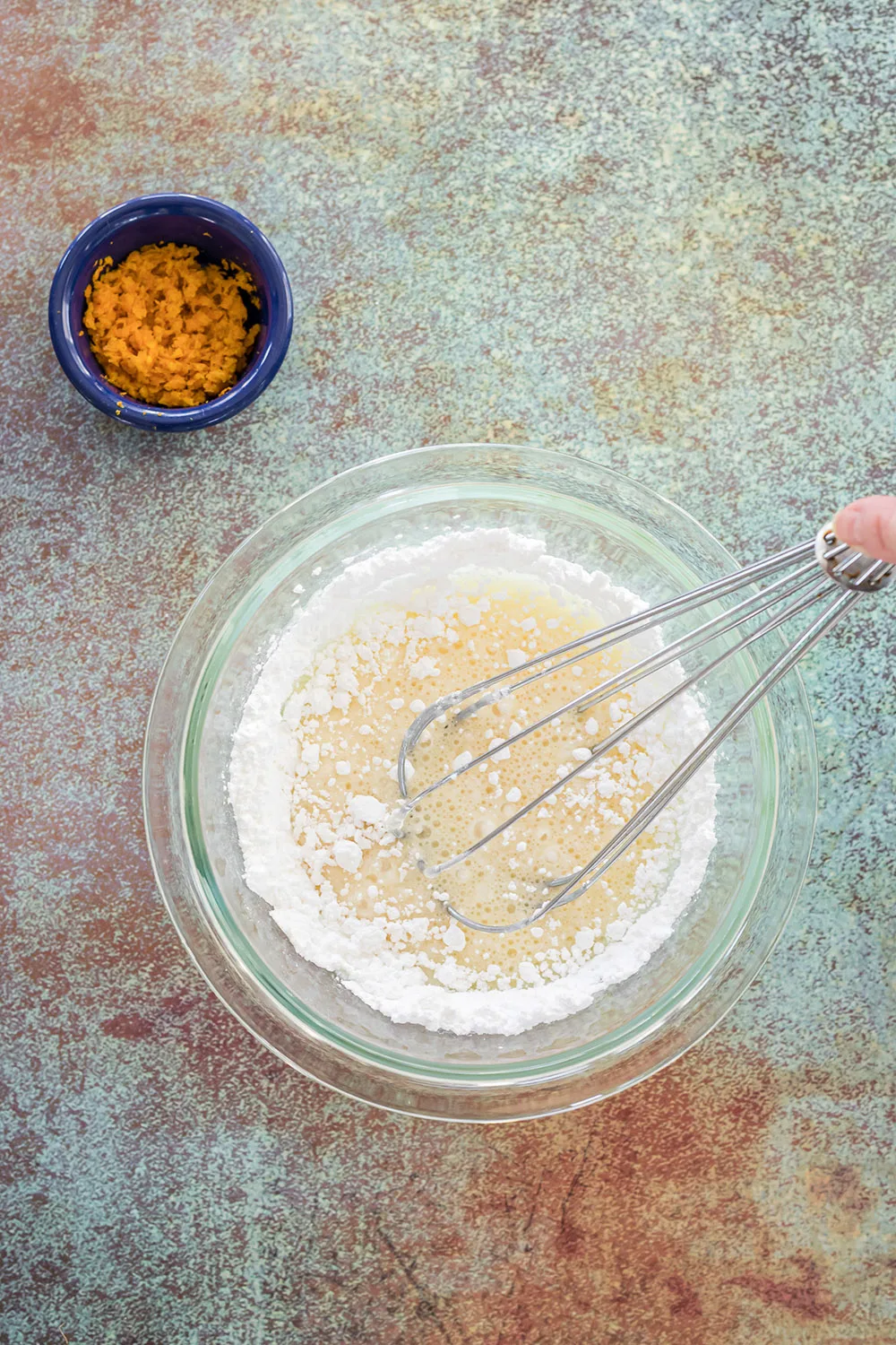 Whisking orange juice into powdered sugar.