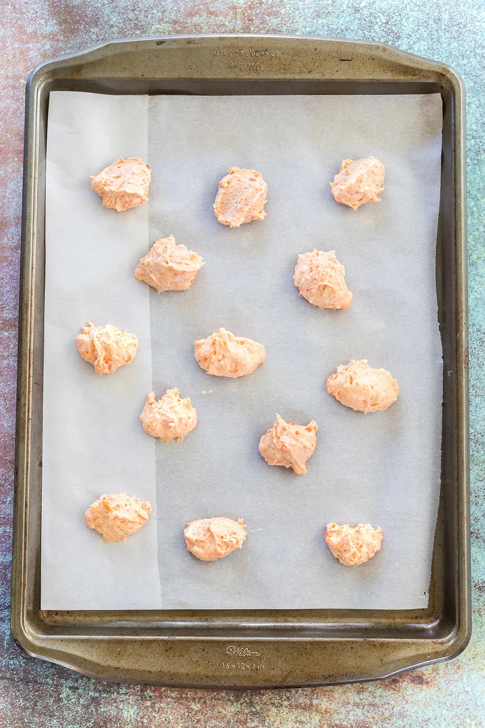 Drops of cookie dough on a baking sheet.