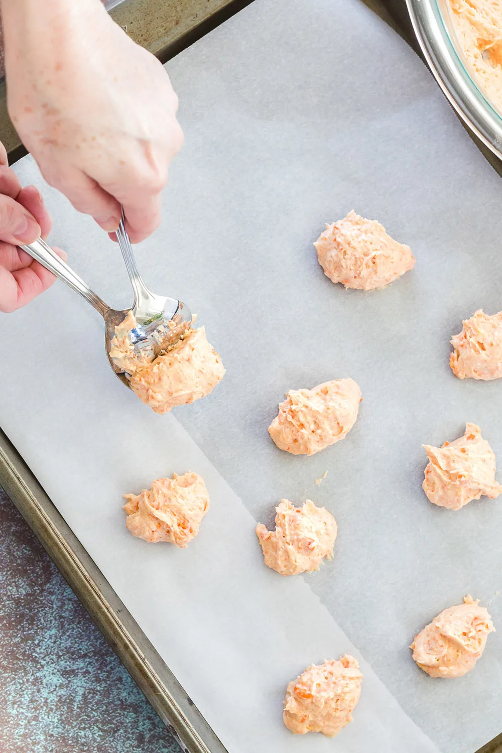 Adding cookie batter to a prepared baking sheet. 