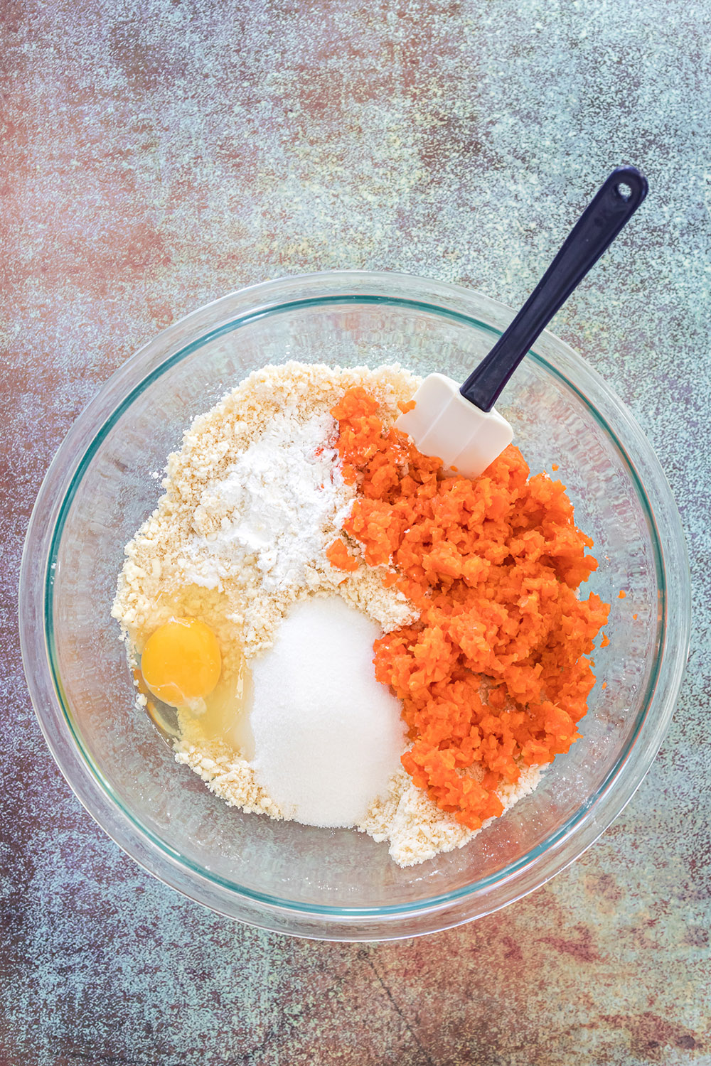 Carrots, flour, butter, and egg in a mixing bowl.