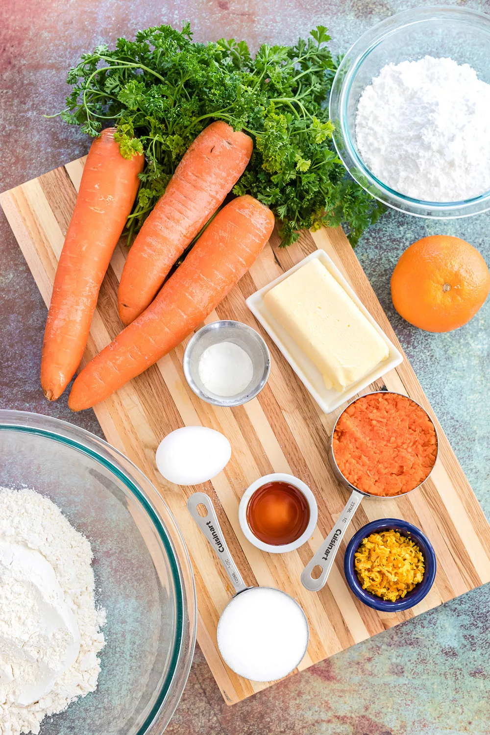 Carrots, sugar, flour, and other ingredients on a board.