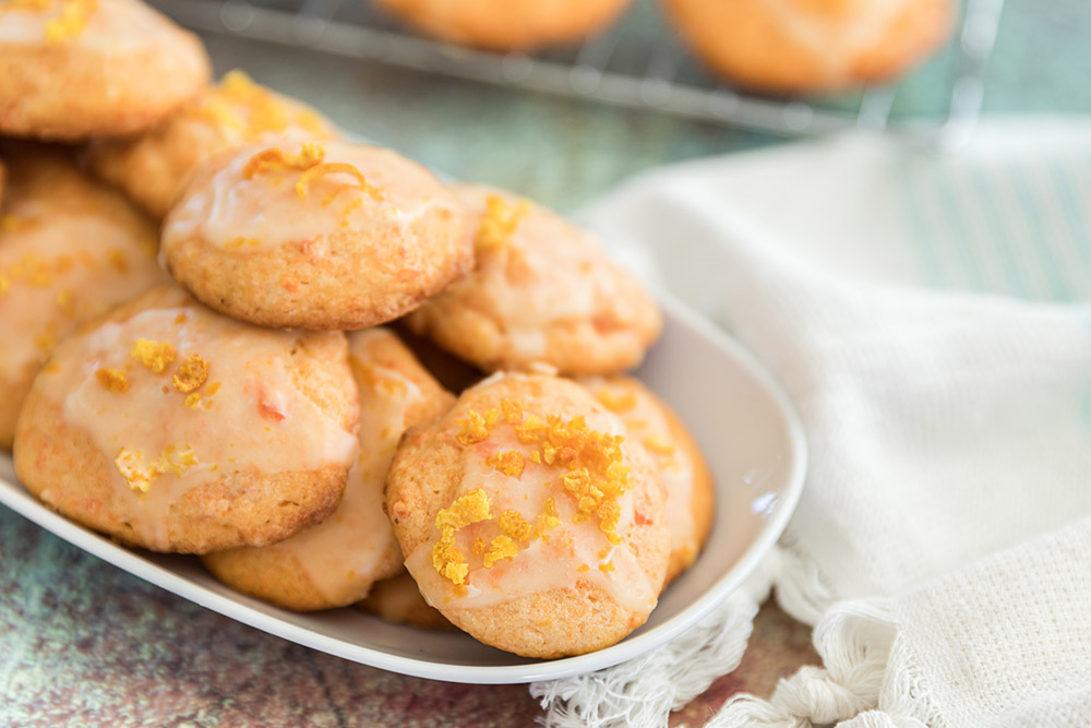 Carrot cookies with an orange glaze on a tray.