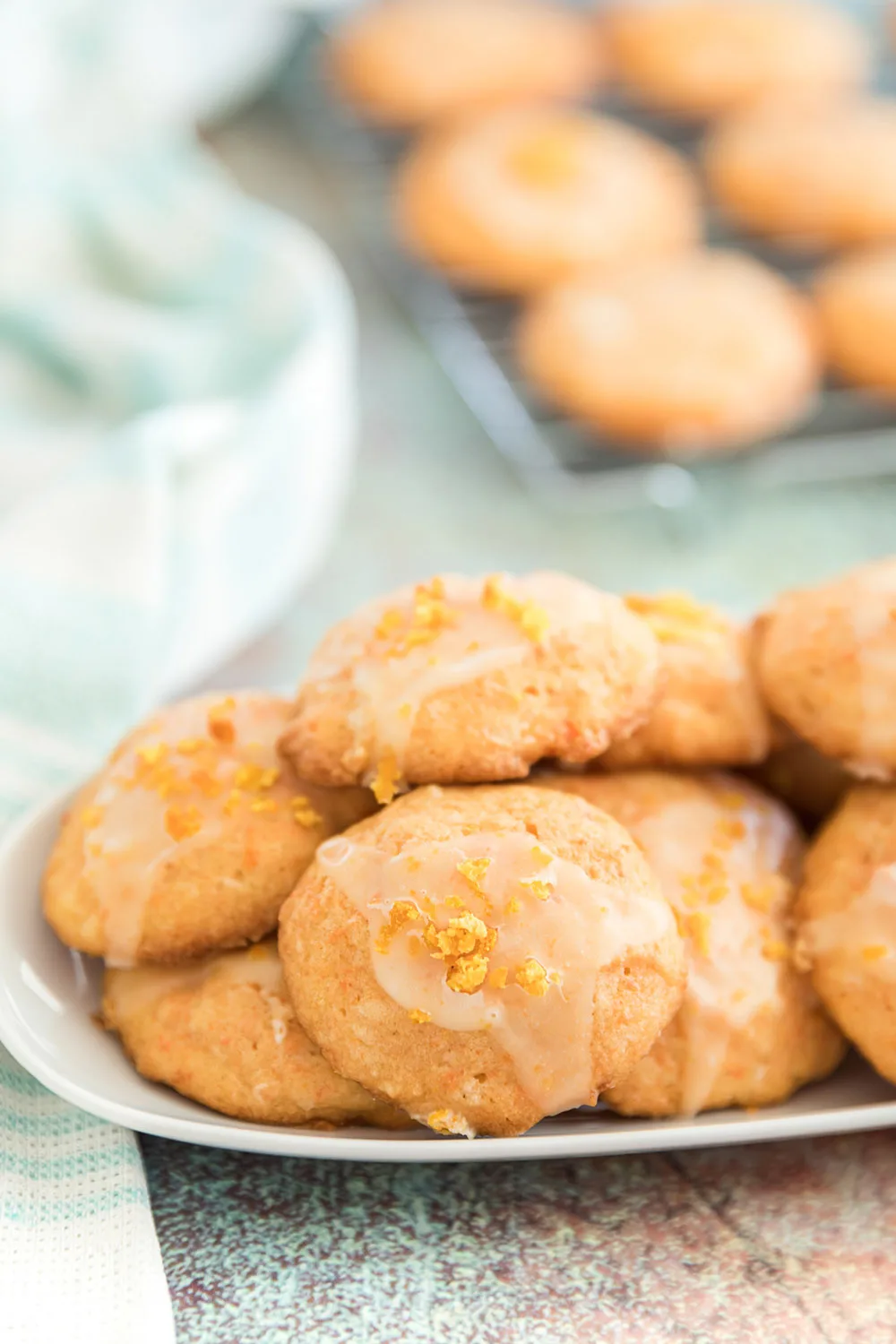 Plate of carrot cookies with more cooling on a rack in the background.