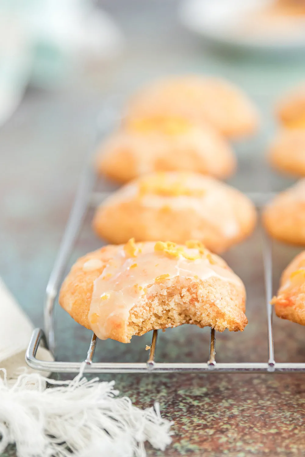 Orange cookie with a bite taken out of it on a rack.