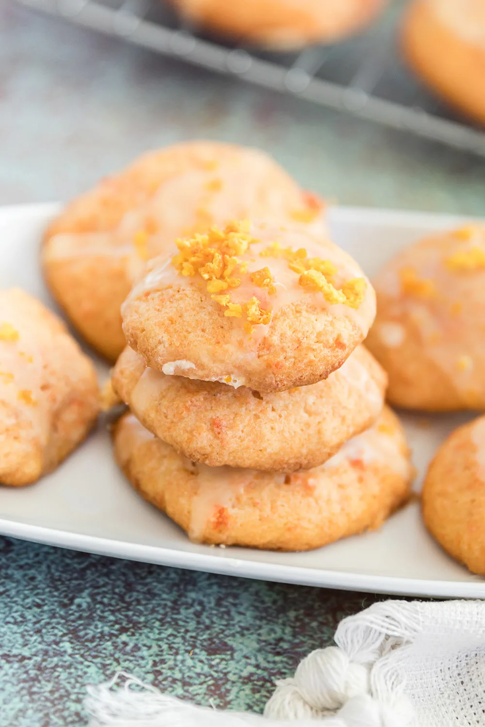 Stacked cookies on a tray. The cookies have a carrot glaze and are orange in color. 