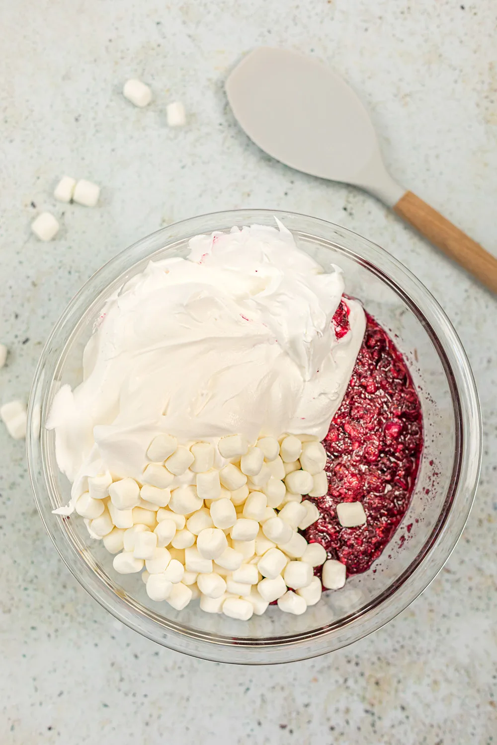 Marshmallows, whipped cream, and cranberries in a bowl.