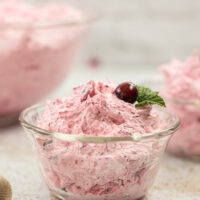 Dish with a fluffy pink salad topped with a cranberry.
