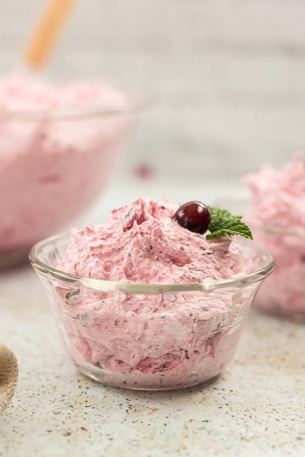 Dish with a fluffy pink salad topped with a cranberry.