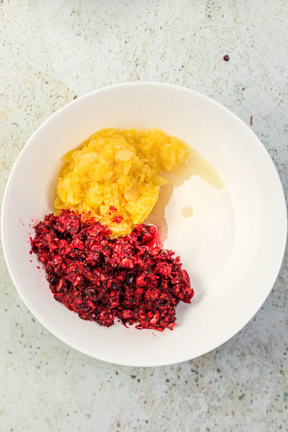 Pineapple, chopped cranberries, and sugar in a bowl. 