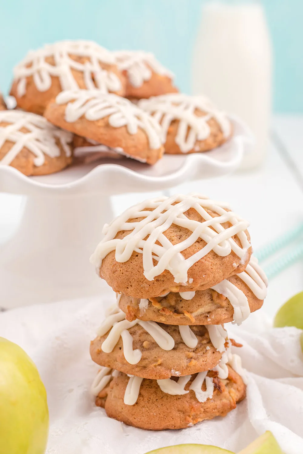 Cookies in a stack and on a tray with milk and apples.