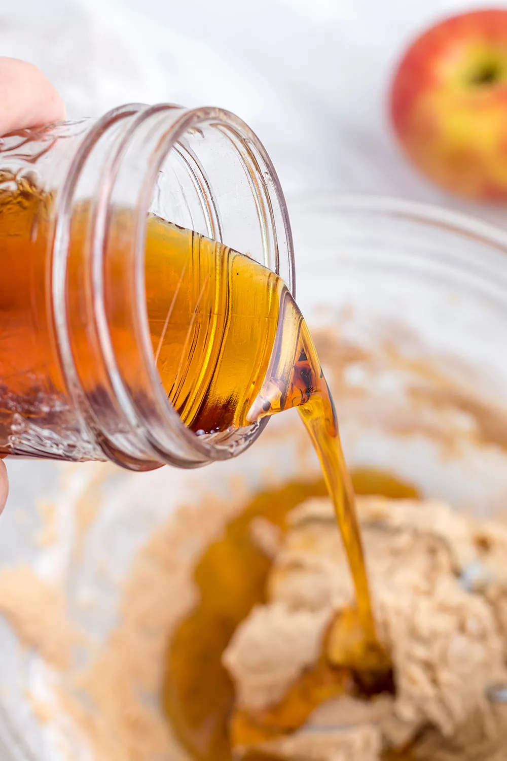 Pouring syrup into batter in a bowl.