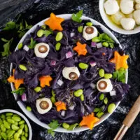 Bowl of bat pasta salad on a table surrounded by ingredients.