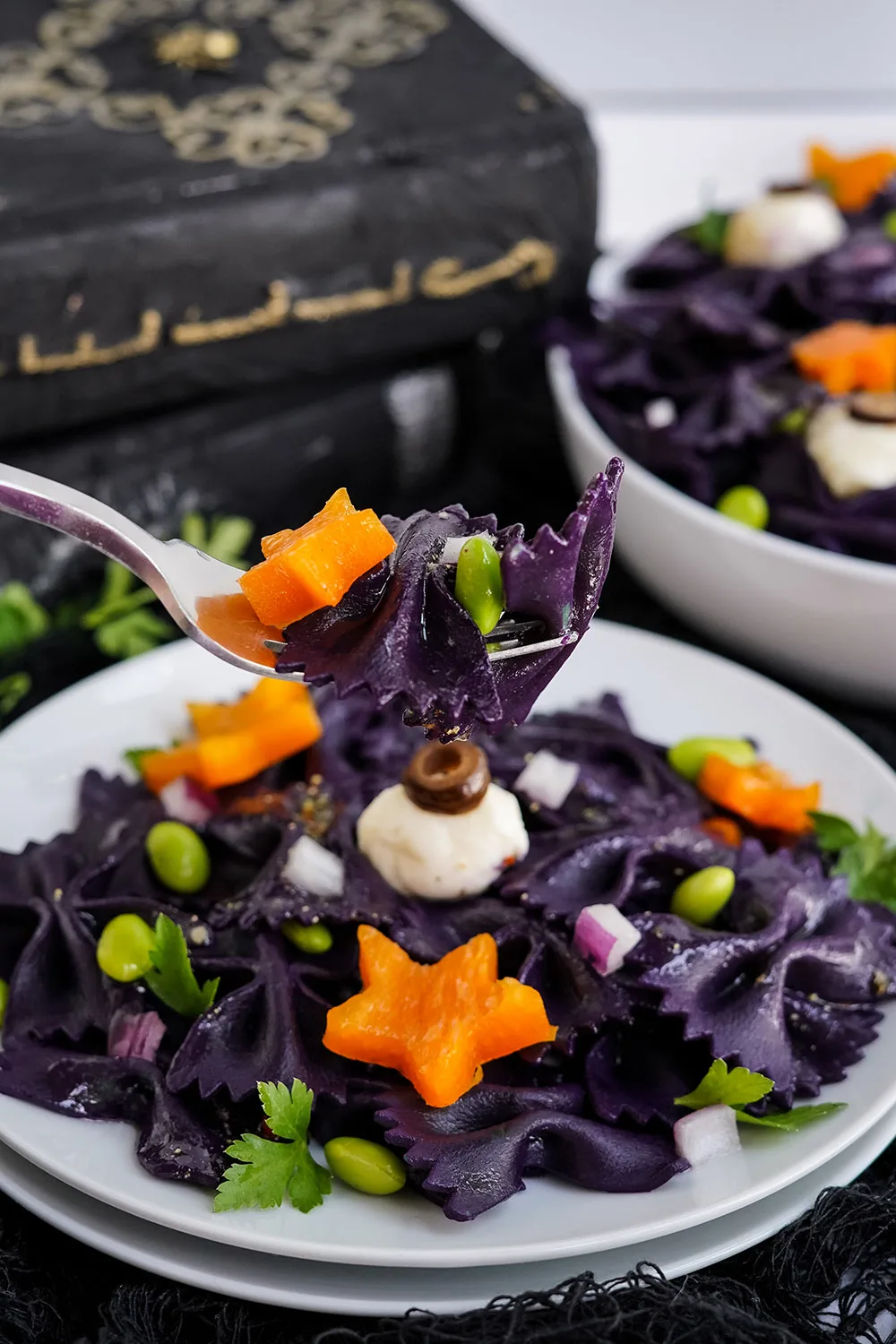 Forkful of black pasta salad with the bowl in the background.