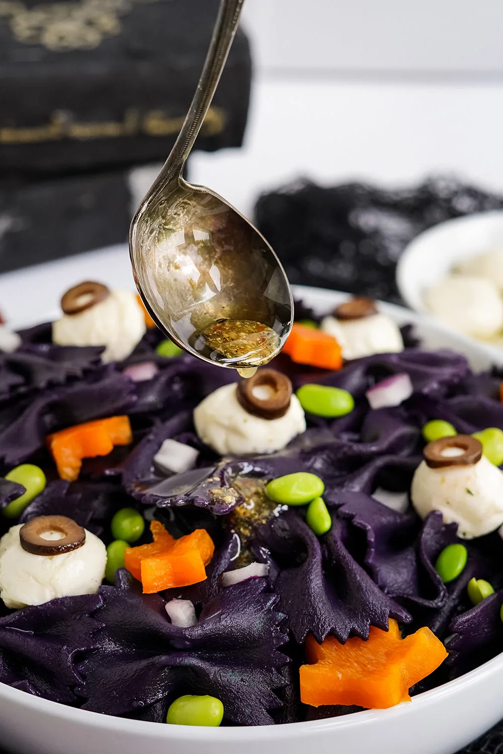 Pouring dressing on top of Halloween pasta salad.