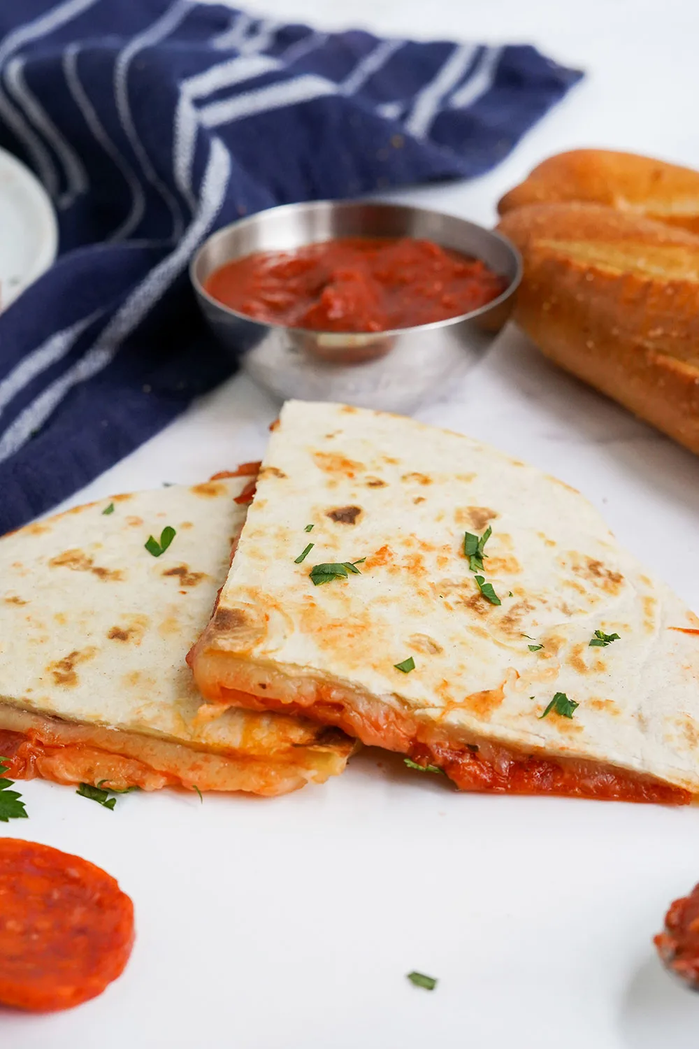 Two quesadilla slices on a table with dipping sauce.