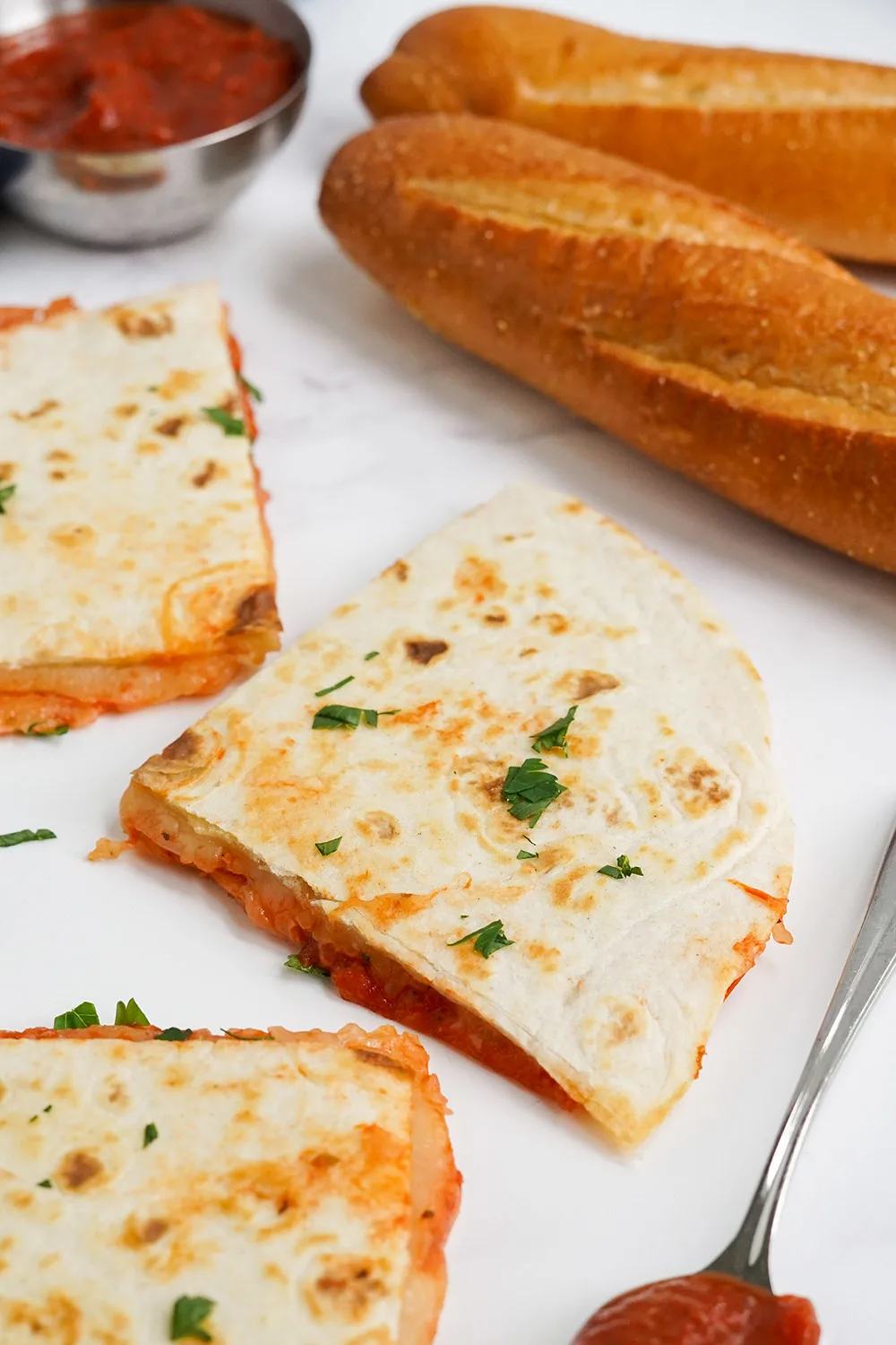 Sliced pepperoni pizza quesadillas next to loaves of bread.