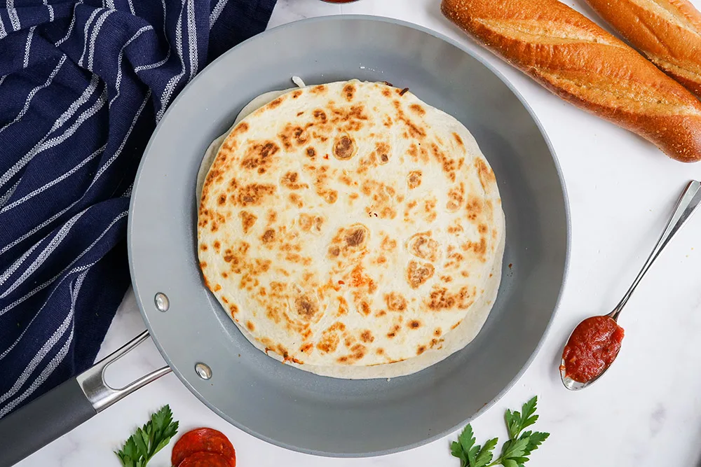 Golden brown tortilla in a skillet.