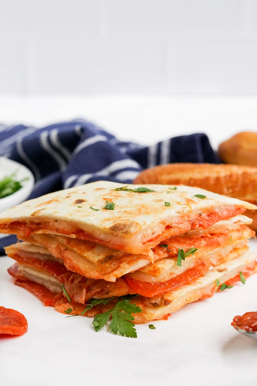 Stacked pizza quesadillas with parsley and a blue napkin.