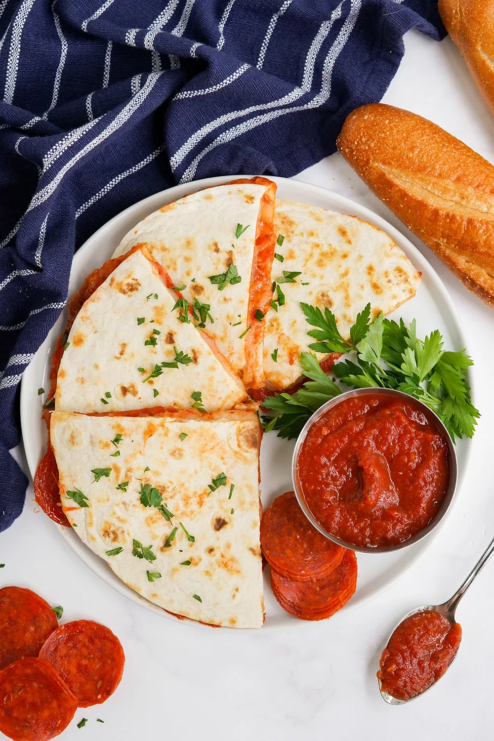 Quesadillas on a plate with sauce, meat, and loaves of bread.