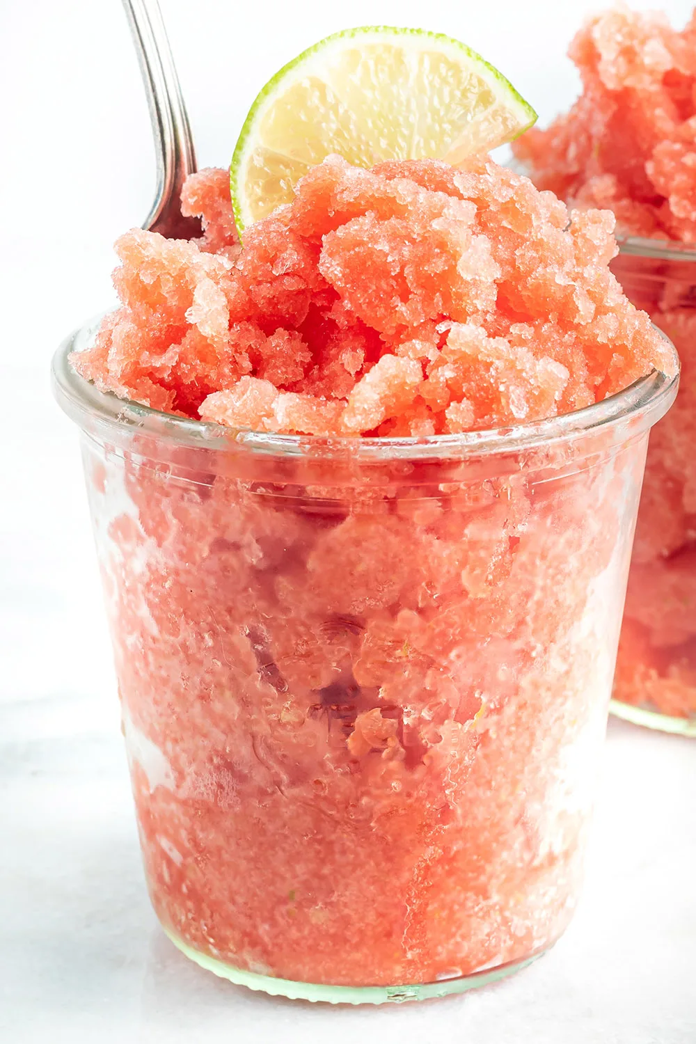 Clearn cup full of watermelon granita topped with a lime slice.