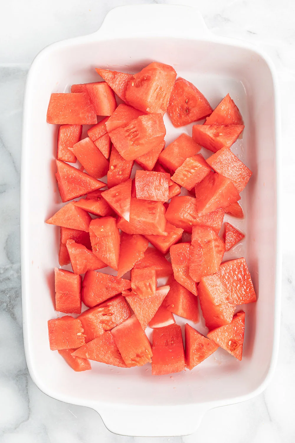Cubes of watermelon in a white dish.