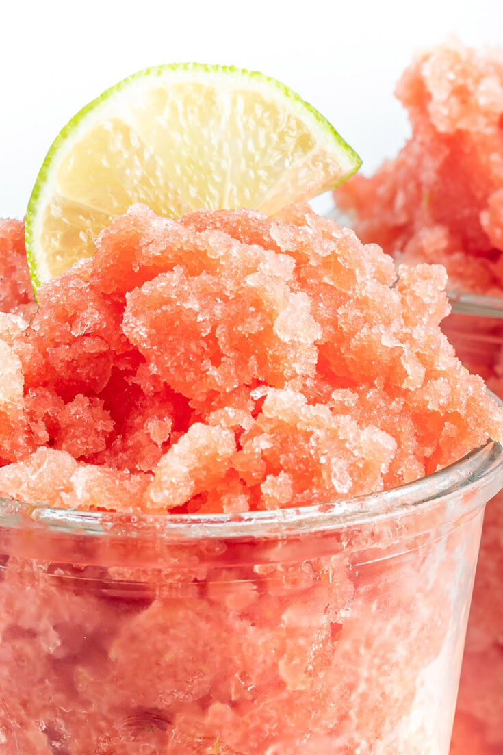 Watermelon granita in a clear cup with a slice of lime on top.