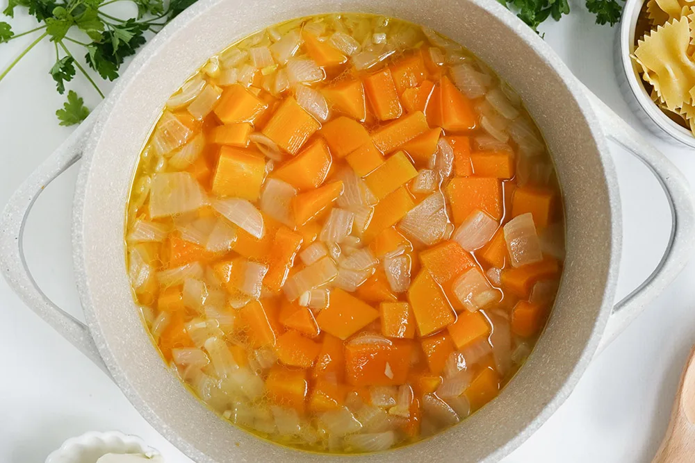 Broth in a bowl with squash and garlic.
