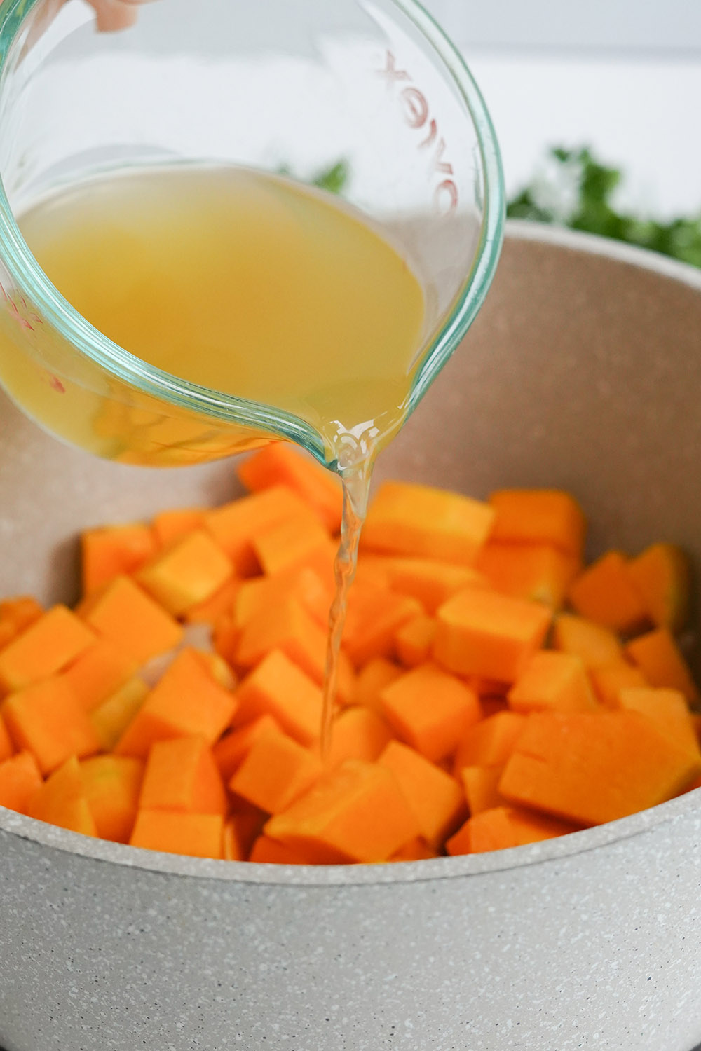 Pouring broth on top of butternut squash
