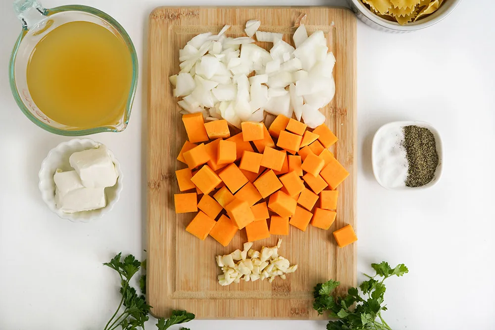 Chopped squash, onion, garlic, and other ingredients on a board.